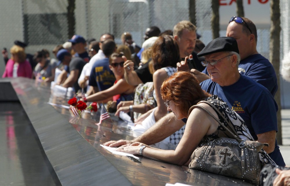Visitors make rubbings from panels containing the names of the victims of the attacks, on the first day that the 9/11 Memorial was opened to the public at the World Trade Center site in New York