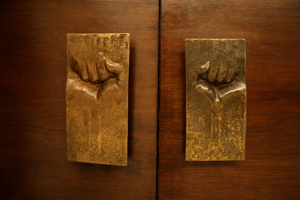 Tiradores de puerta del escultor Ricardo Mesa. En Dictadura se invirtió el sentido de las manos. (Rescatada de edificio original) © Plataforma Urbana.