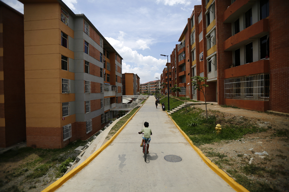 A boy rides a bicycle among apartment buildings in Ciudad Caribia outside Caracas
