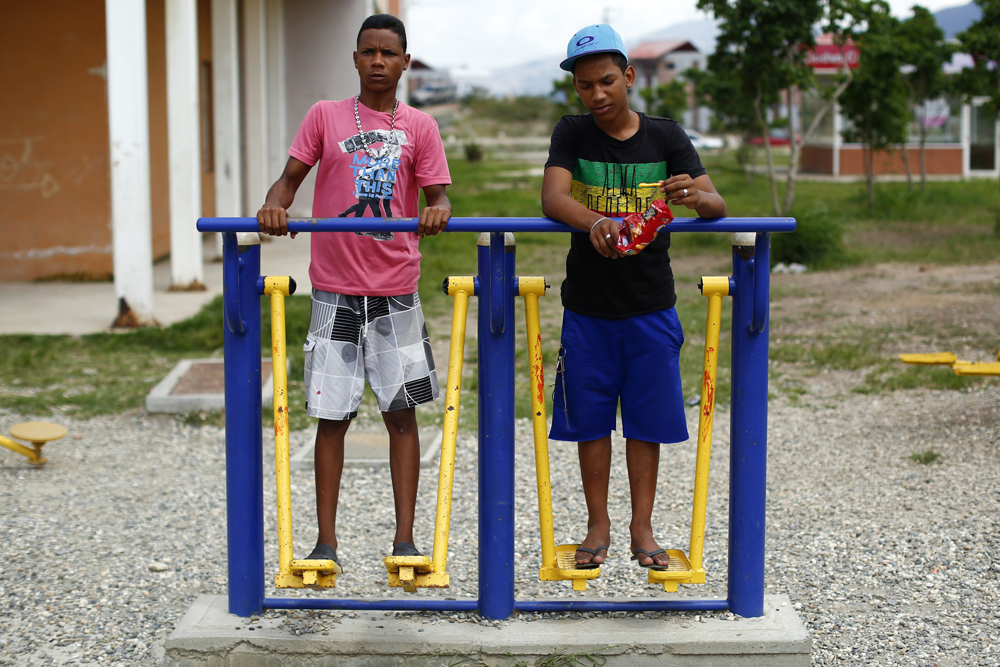 Boys step on public exercise machines in Ciudad Caribia outside Caracas